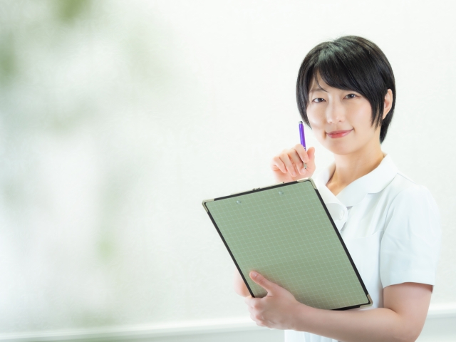バインダーを持って微笑む看護師