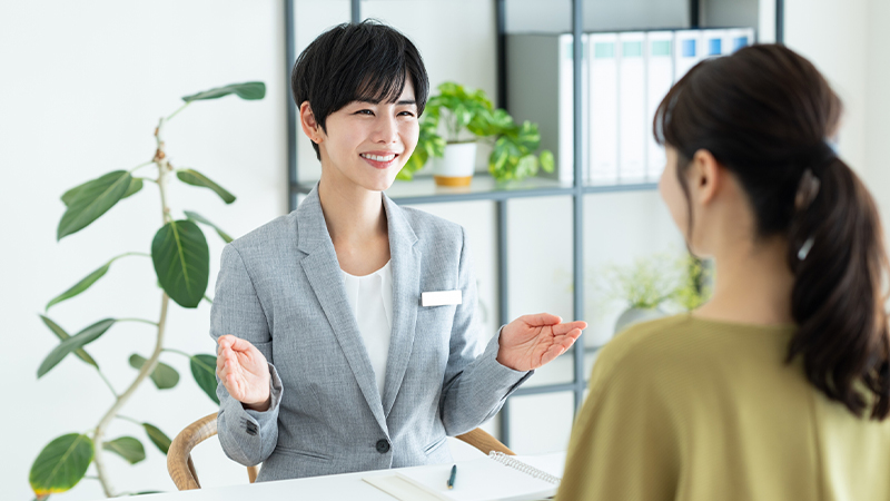 美容クリニックで相談者に笑顔で説明するカウンセラー