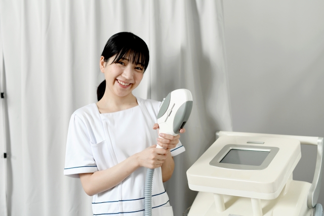 レーザー機器を持ってほほえむ美容皮膚科のスタッフ